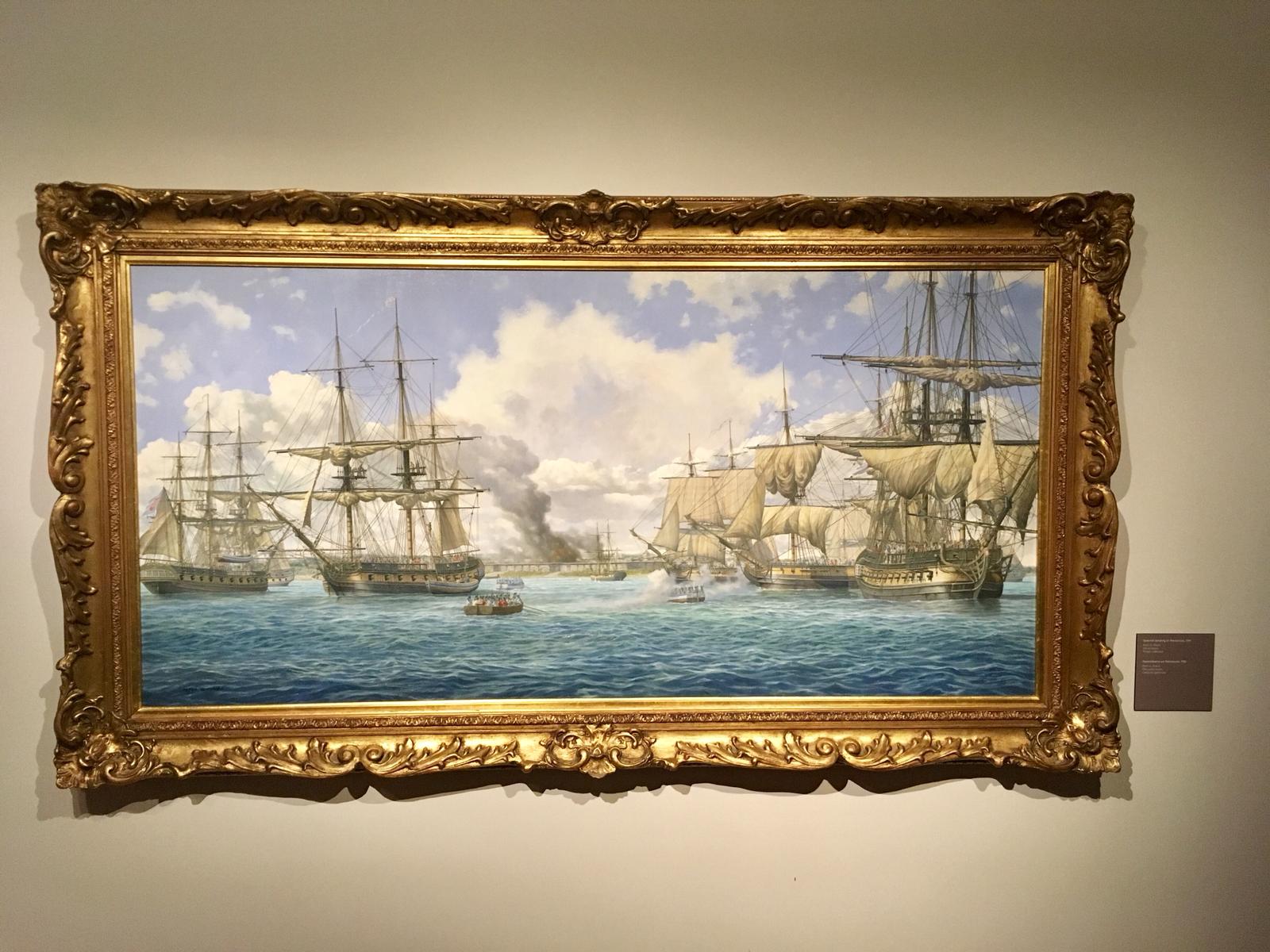 Vista frontal del óleo de Pensacola en su marco dorado tallado, colgado en pared clara con su cartela junto al borde derecho