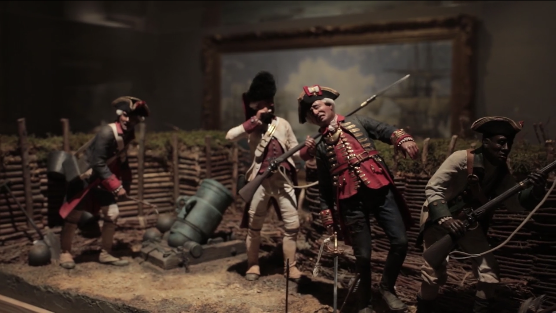 Cinco figuras de soldados del siglo XVIII con mosquetes y un mortero en las trincheras de un diorama, con una pintura naval enmarcada al fondo