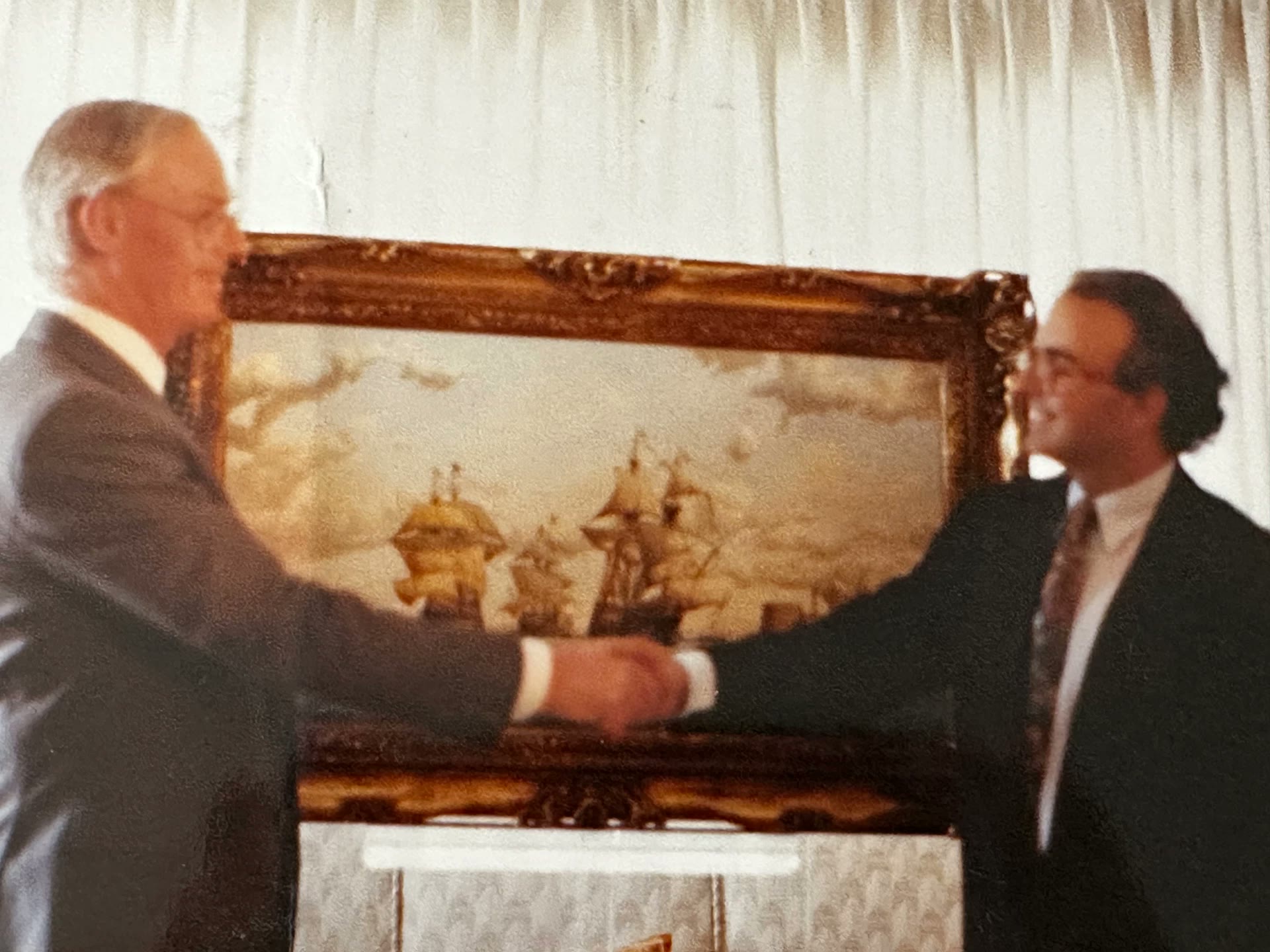 Rafael Pedroso y Peter G. Power se dan la mano ante la marina enmarcada, otra toma de la misma escena.
